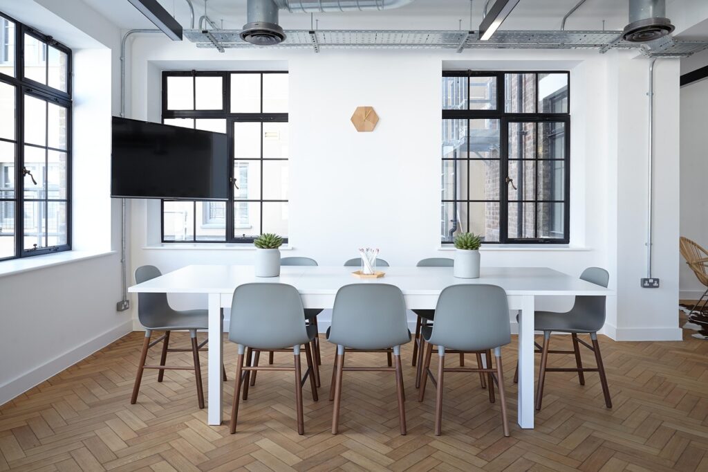 Office cleaning London meeting room with long table, grey chairs, large windows, and light wood floor